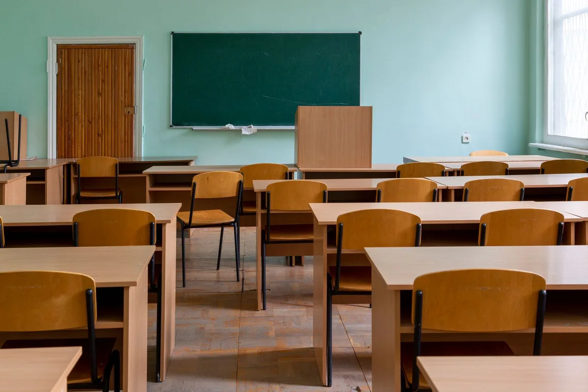 Empty classroom with wooden desks and a green chalkboard