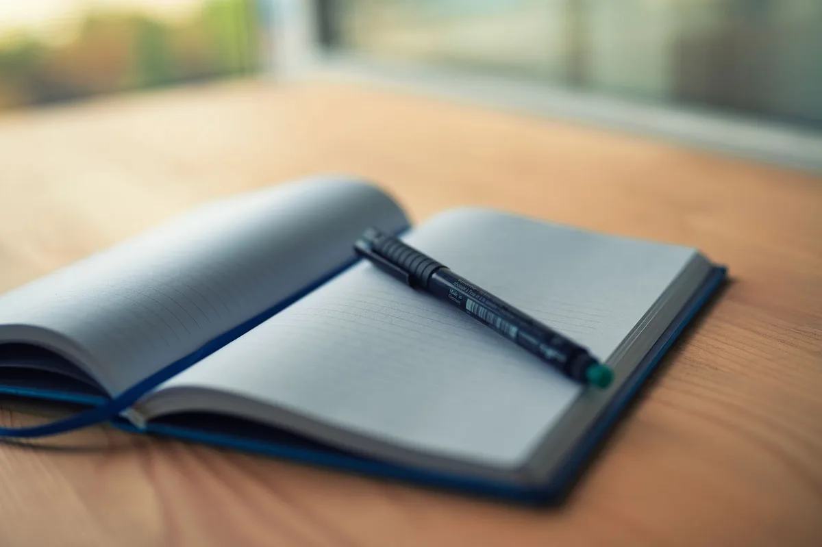 Open lined notebook with a pen on a wooden desk