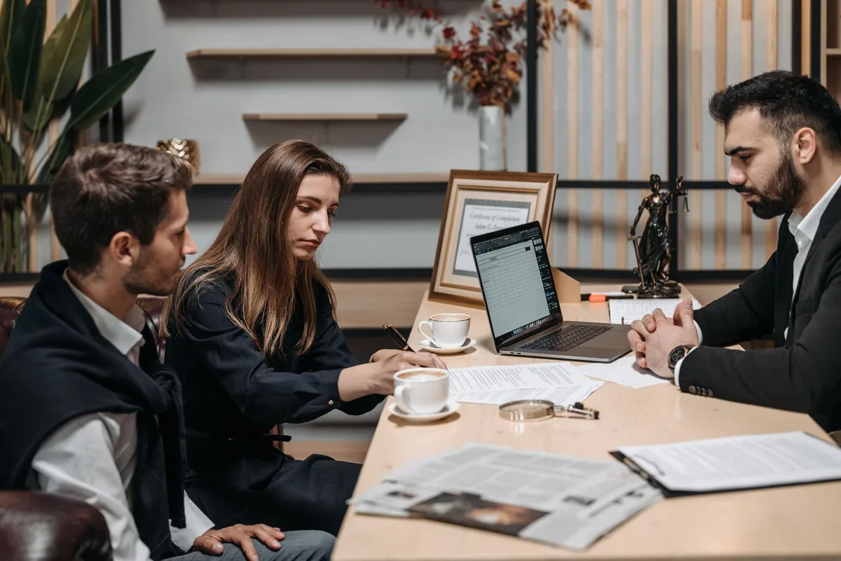 Three professionals discussing documents over coffee