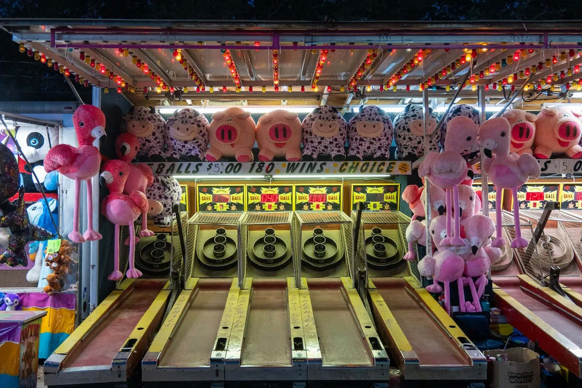 Skee ball arcade with plush toys at a nighttime fair