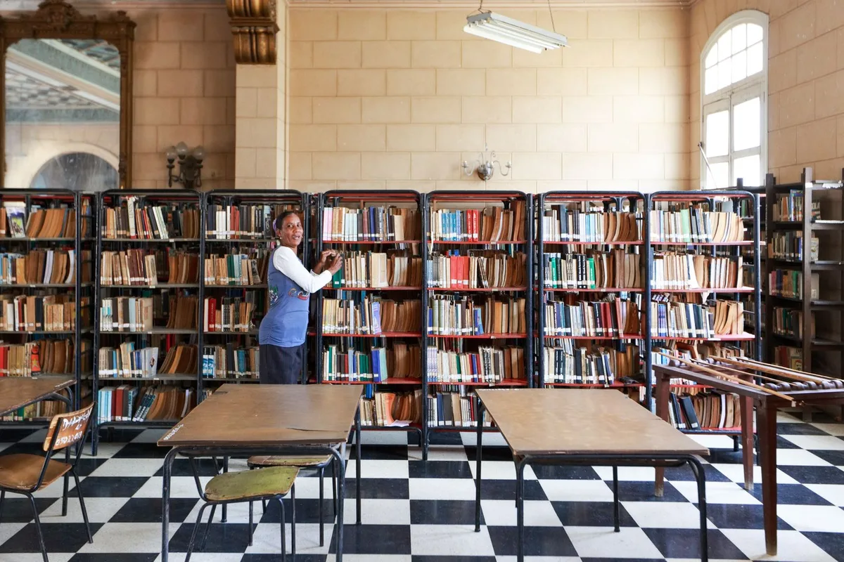 Librarian organizing books in a classic library
